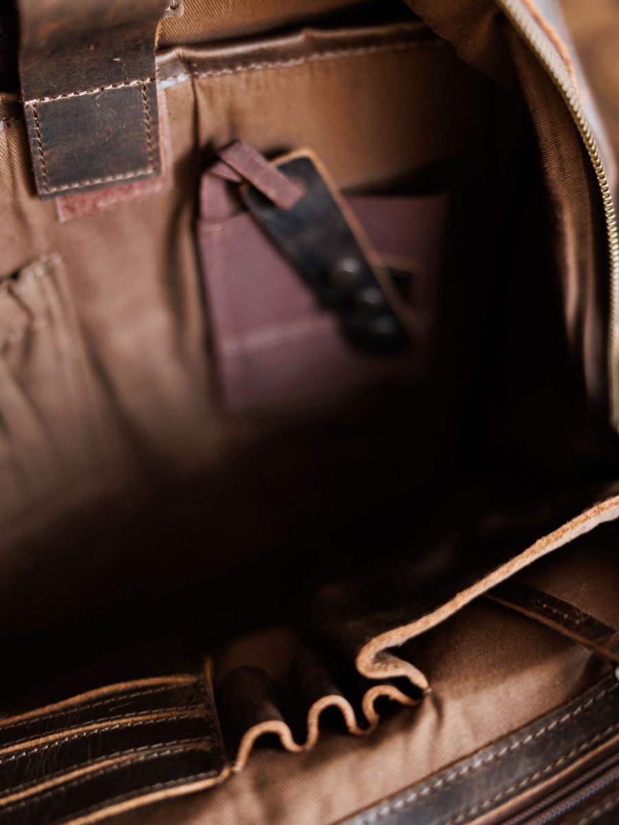 Close-up of the Mohave Backpack by Savannah Sevens western life{&}style, showing organized compartments and pockets with dark sunglasses tucked into one pocket. By STS> 