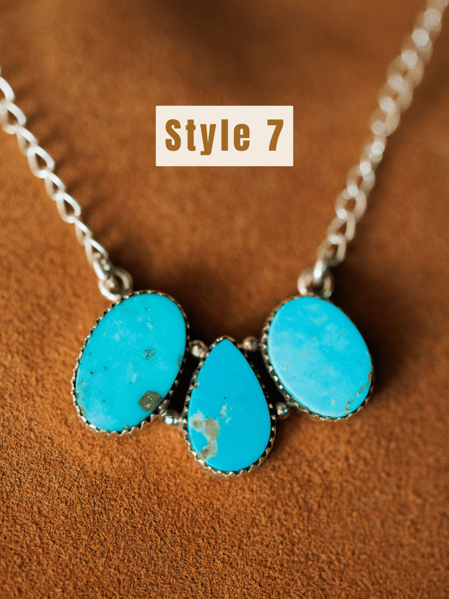 The Montrose Necklace by Savannah Sevens western life{&}style features three blue Red River Turquoise stones—two oval and one teardrop-shaped—set in sterling silver, displayed on a brown textured surface with "Style 7" text above.