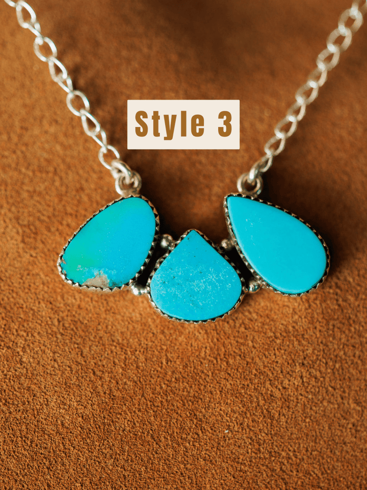 The Montrose Necklace by Savannah Sevens western life{&}style features three teardrop turquoise stones set in sterling silver, shown on a brown suede background. "Style 3" is displayed above the necklace in bold black text on a white box.