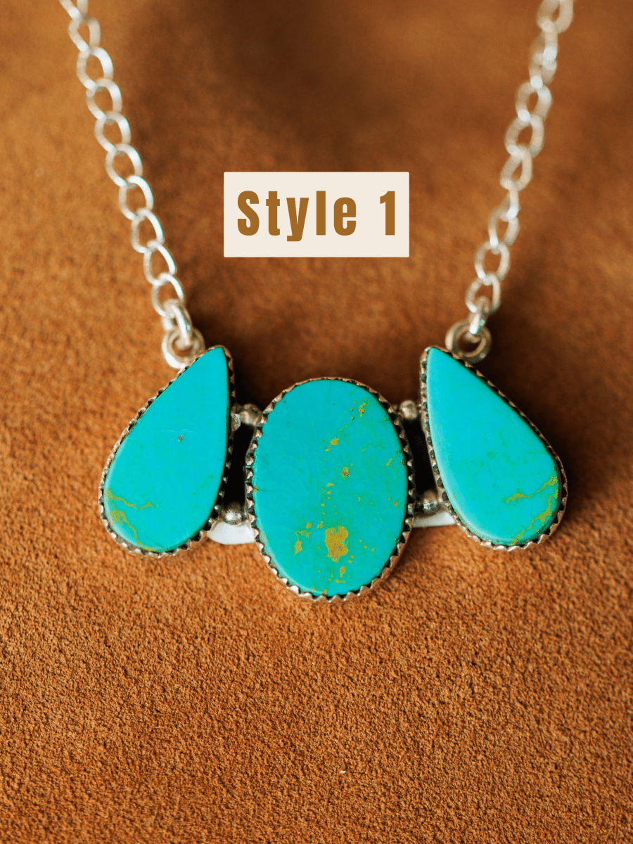 Style 1: The Montrose Necklace by Savannah Sevens western life{&}style features three Red River Turquoise stones—two teardrop and one oval—in ornate sterling silver settings on a brown suede background.