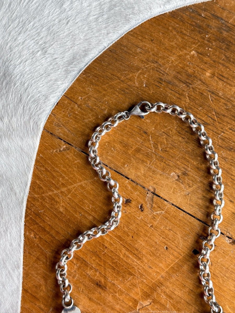 The Morado Necklace & Earrings Set by Savannah Sevens western life&style is displayed in a loose heart shape on wood beside textured white fabric.