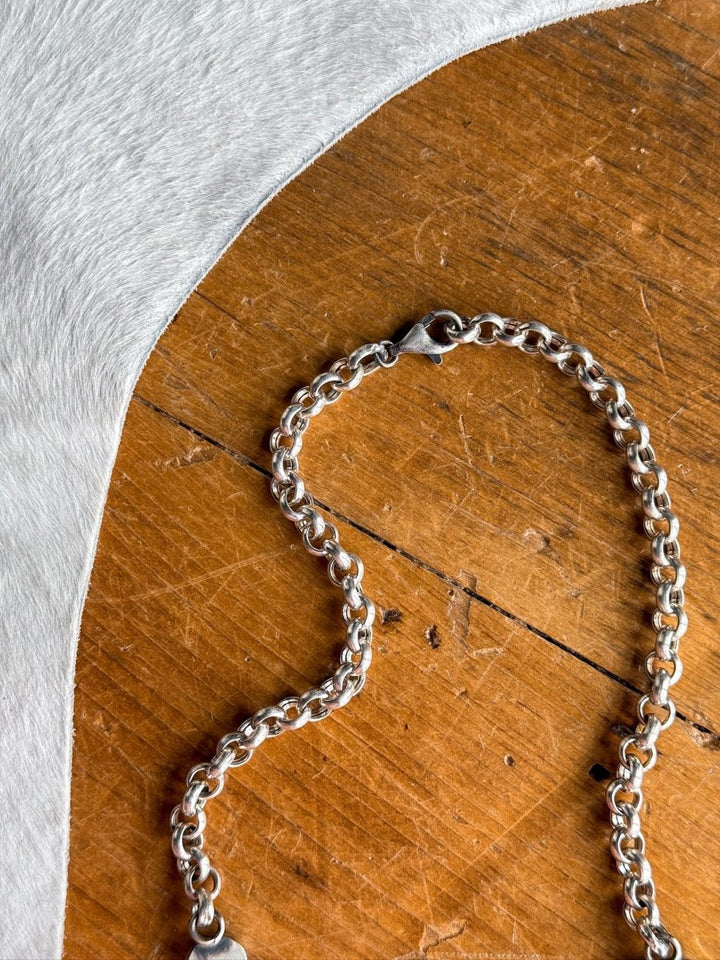 The Morado Necklace & Earrings Set by Savannah Sevens western life&style is displayed in a loose heart shape on wood beside textured white fabric.