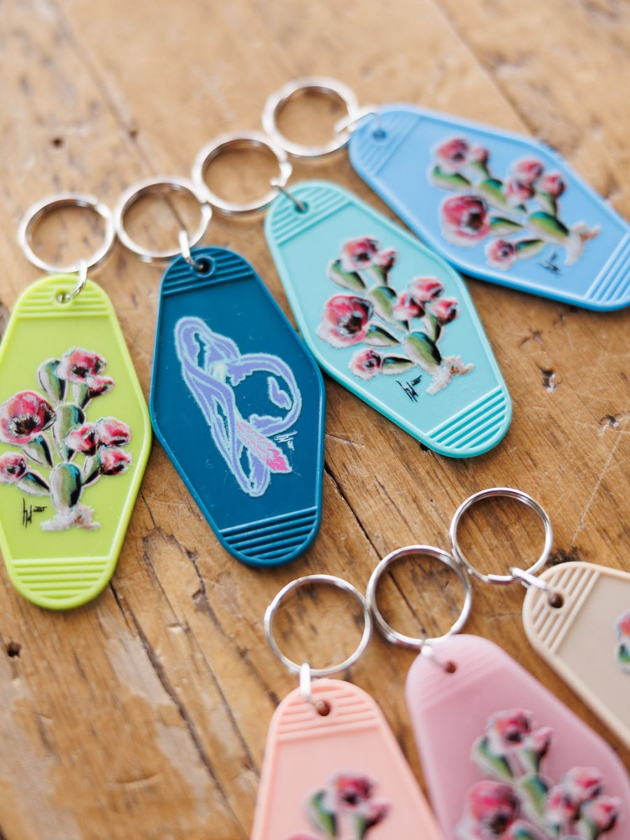 Five Motel Keychains by Savannah Sevens western life{&}style feature vintage-style cactus and flower designs in blue, green, dark teal, peach, and tan—perfect for a Western motel vibe or as a unique purse accessory.