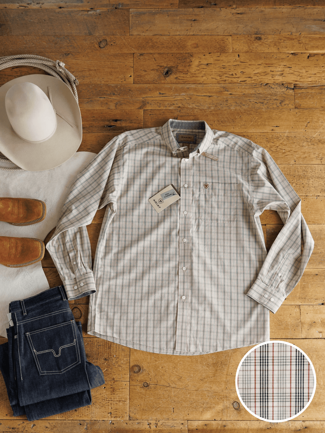 The Murtaugh Ariat Men's Natural Plaid Button Up from Savannah Sevens western life{&}style is laid out on a wooden floor with jeans, brown cowboy boots, and a white cowboy hat. A circular inset shows a close-up of the plaid fabric pattern.