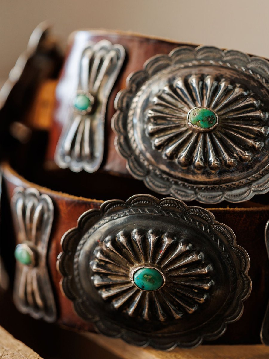 A close-up of the New Mexico Belt by Savannah Sevens western life{&}style, featuring large silver conchos with scalloped edges and central turquoise stones. Detailed engraving and raised patterns showcase its vintage-inspired design.