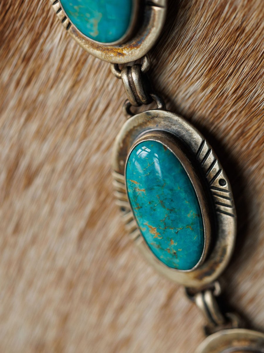 Close-up of the Nogales Necklace by Savannah Sevens western life{&}style, featuring large Kingman turquoise stones and sterling silver, displayed on textured brown cowhide.