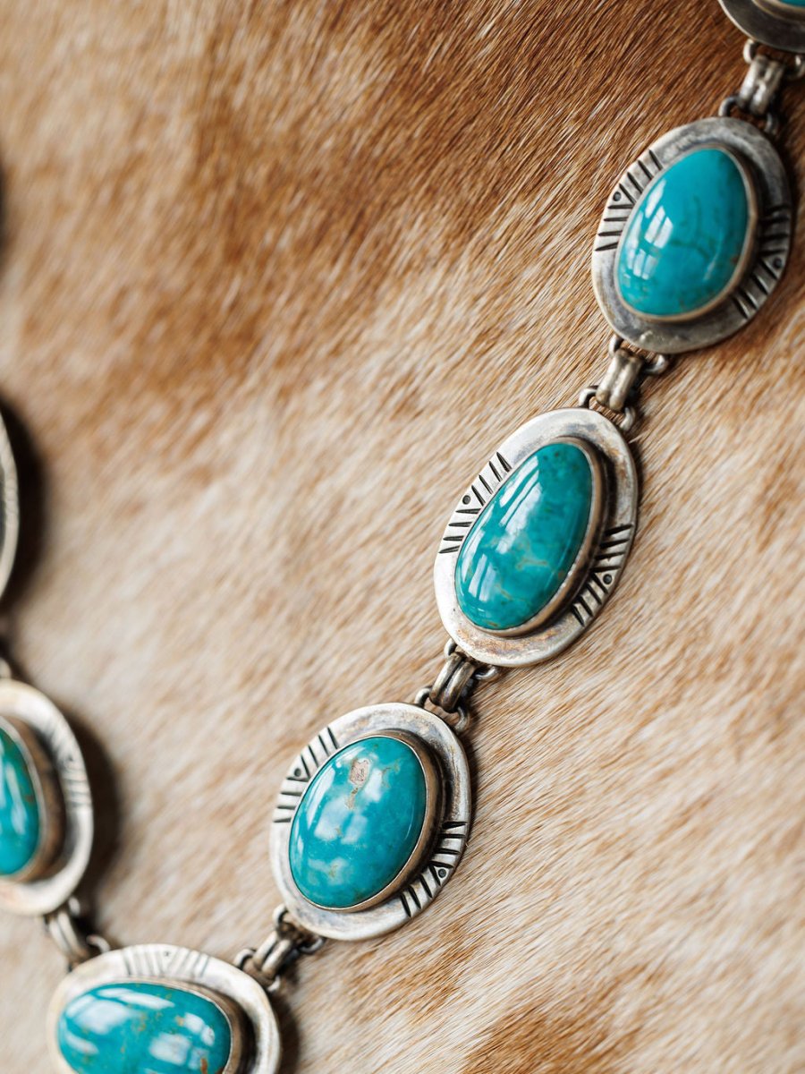 Close-up of the Nogales Necklace by Savannah Sevens western life{&}style, showcasing handmade oval Kingman turquoise stones set in engraved sterling silver on a light brown textured fur background.