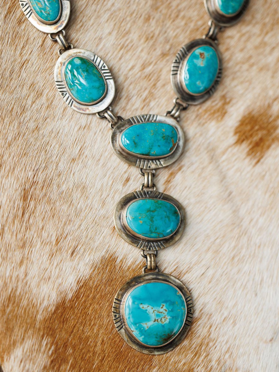 The Nogales Necklace by Savannah Sevens western life{&}style, featuring large oval Kingman turquoise stones, is showcased on a brown and white animal hide background.