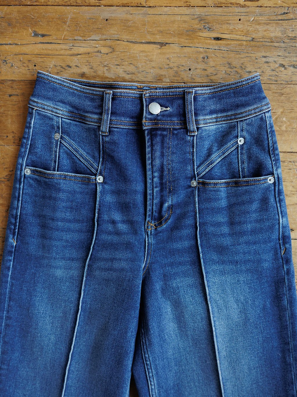 A pair of Savannah Sevens western life{&}style The Oakley High Rise Slim Wide Leg Jeans with front seams and four front pockets, laid flat on a wooden surface.