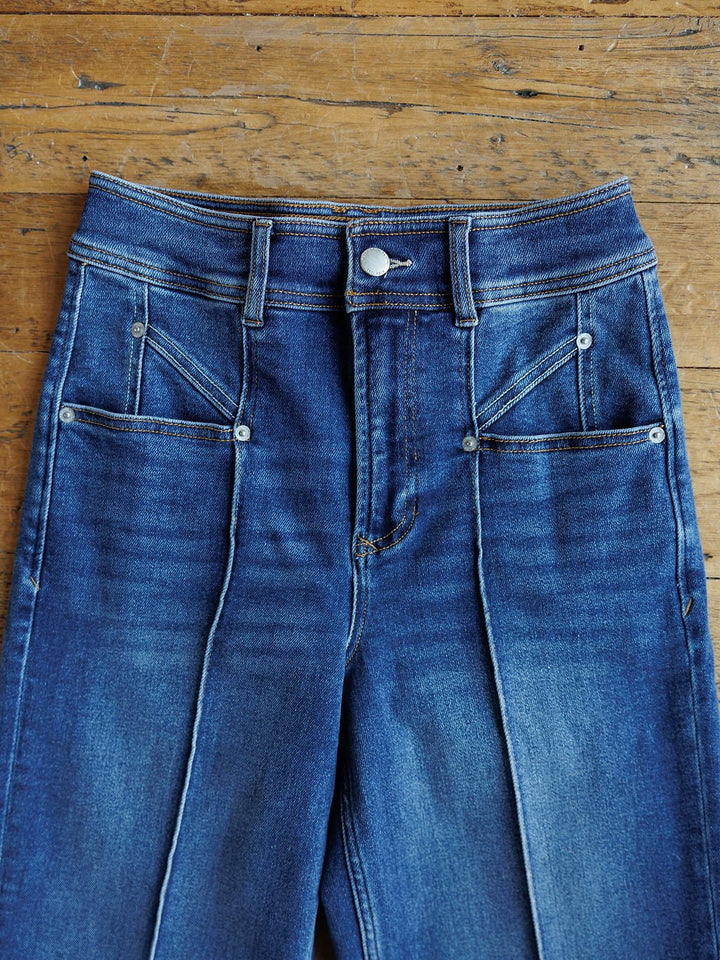 A pair of Savannah Sevens western life{&}style The Oakley High Rise Slim Wide Leg Jeans with front seams and four front pockets, laid flat on a wooden surface.
