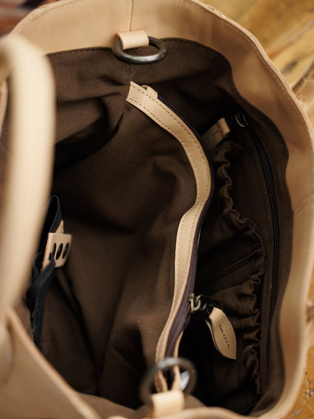 A close-up of the Oketo Buckskin Leather Handbag by Savannah Sevens western life{&}style shows brown lining, a zippered pocket, elastic compartment, leather trim, and a discreet interior holster. Bag by STS. 