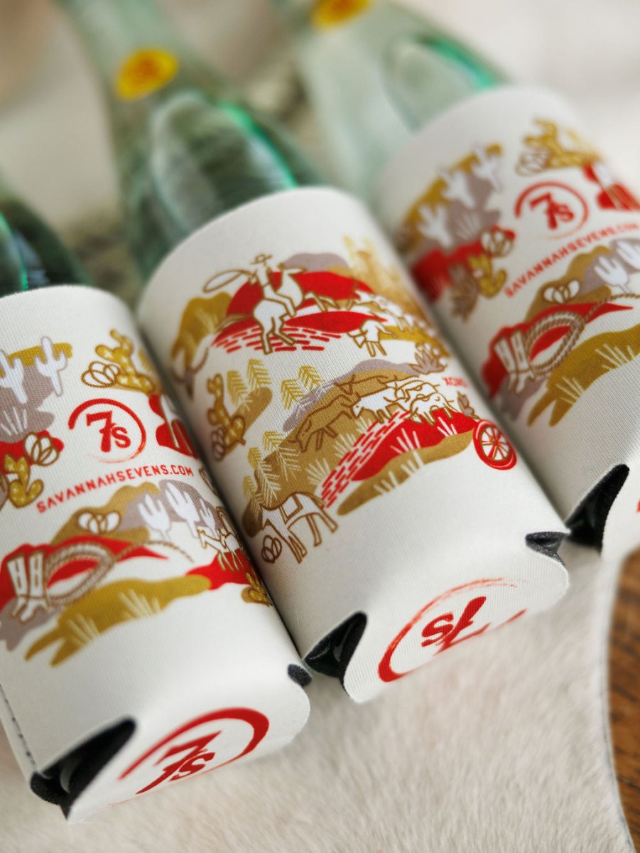 The Out West Koozie by Savannah Sevens western life{&}style includes three glass bottles in white and gold-patterned sleeves with hand-drawn horses, riders, wagons, “savannahsevens.com,” and a red “7S” logo on each sleeve.