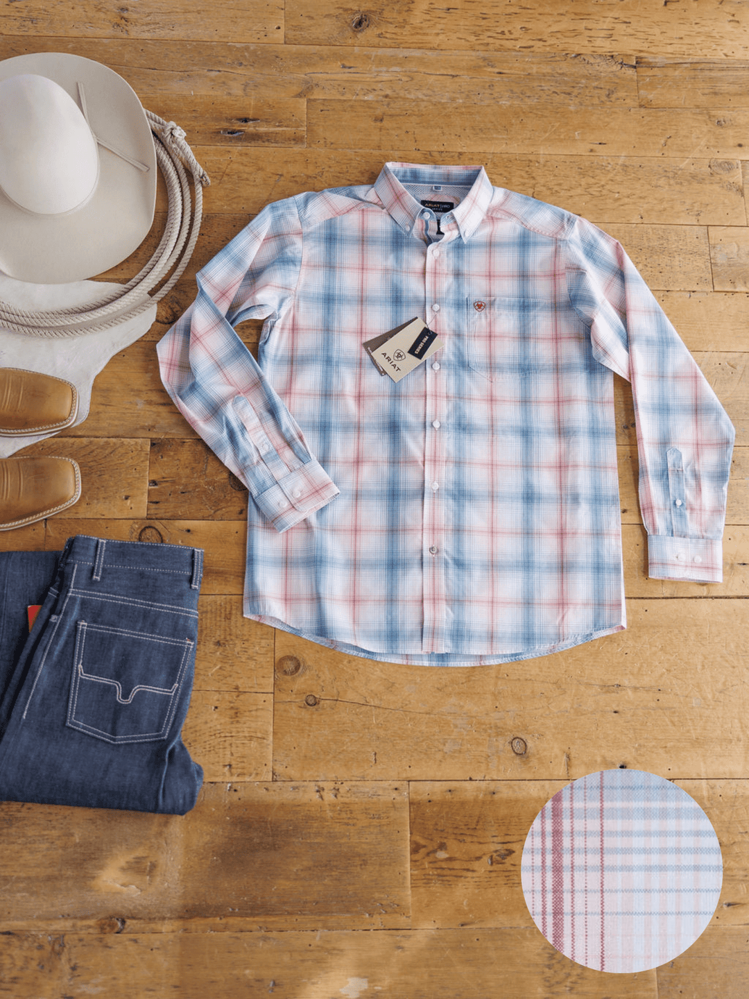 The Palmer Ariat Men's Plaid Button Up by Savannah Sevens western life{&}style is showcased in light blue, pink, and white plaid, laid flat with jeans, cowboy hat, and boots. A close-up highlights its moisture-wicking fabric pattern.