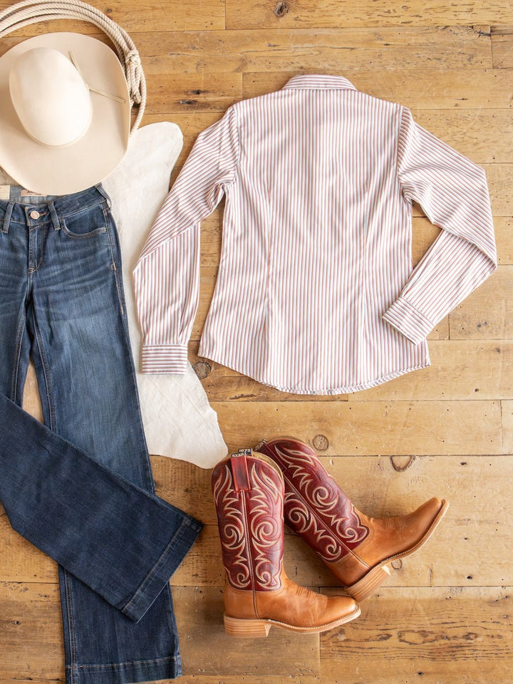 Flat lay of a cowboy hat, Savannah Sevens western life{&}style Patton Striped Tencel Performance Shirt, blue jeans, red embroidered cowboy boots, and a white scarf on a wooden floor.