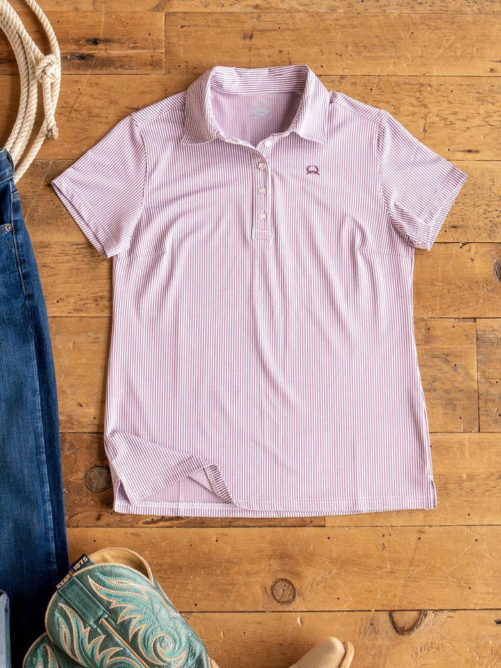 The Payden Burgundy Striped Polo by Savannah Sevens western life{&}style is laid flat on a wooden floor, next to blue jeans and green cowboy boots.