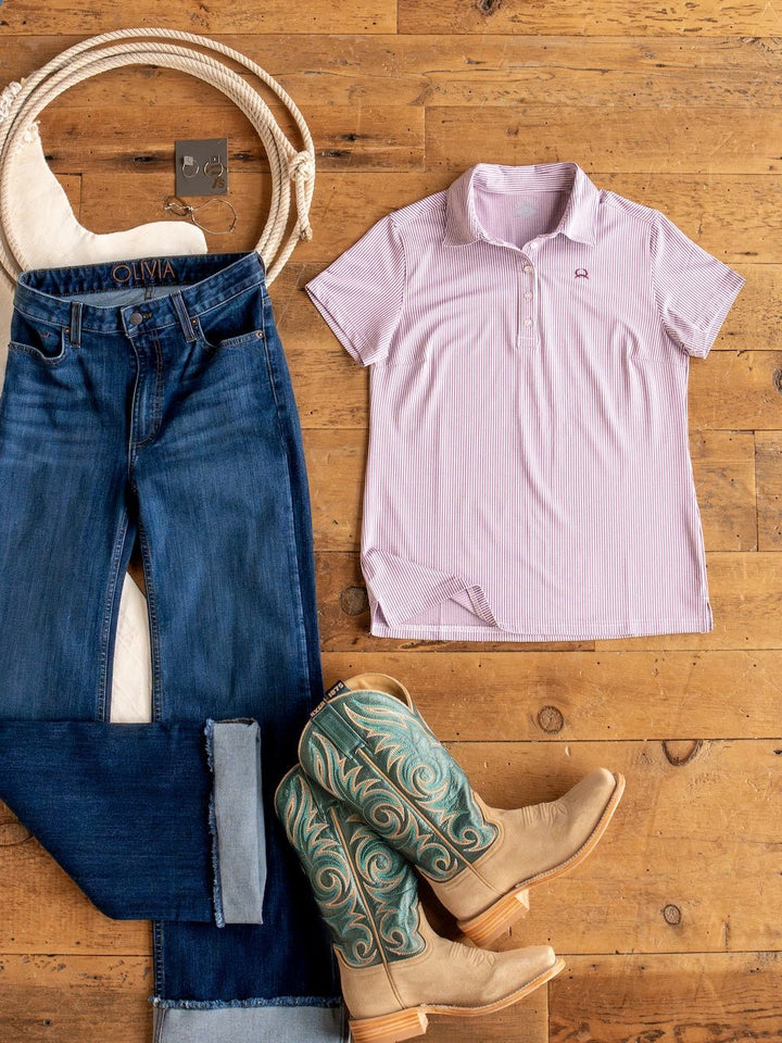 Flat lay of a casual outfit on a wooden floor: blue jeans, the Payden Burgundy Striped Polo by Savannah Sevens western life{&}style, tan cowboy boots with teal embroidery, a white belt, and silver earrings.