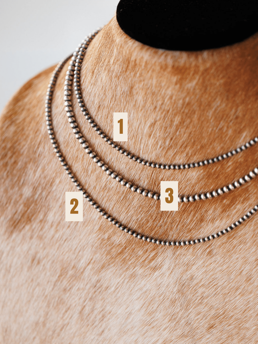 Close-up of a tan dog’s neck wearing three hand-strung Pecos Necklaces by Savannah Sevens western life{&}style, each labeled 1, 2, and 3 top to bottom. A black collar is also worn at the top.