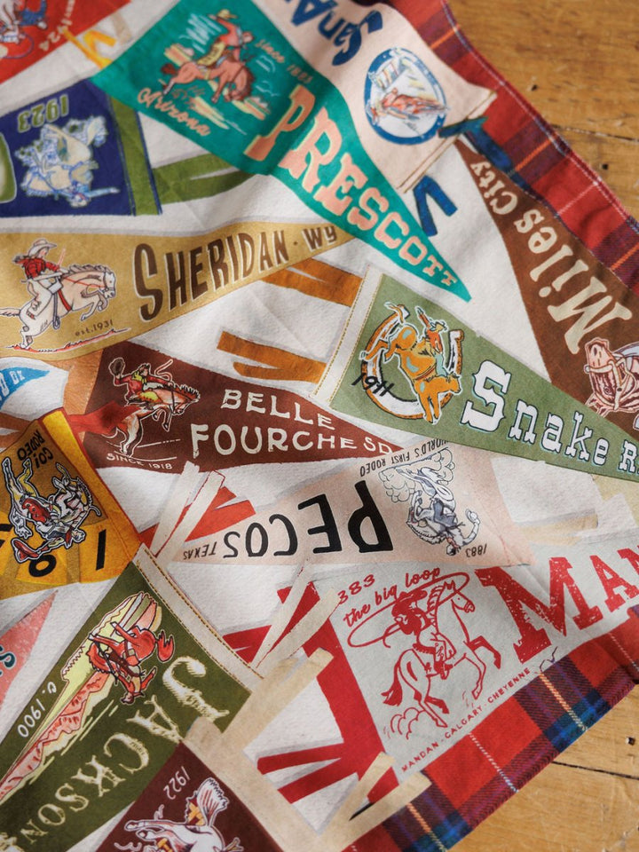 The Pennants Neck Scarf by Savannah Sevens western life{&}style features colorful, vintage rodeo-and-cowboy patches with place names like Prescott, Sheridan, Belle Fourche, and Jackson—perfect for a bold western scarf look.
