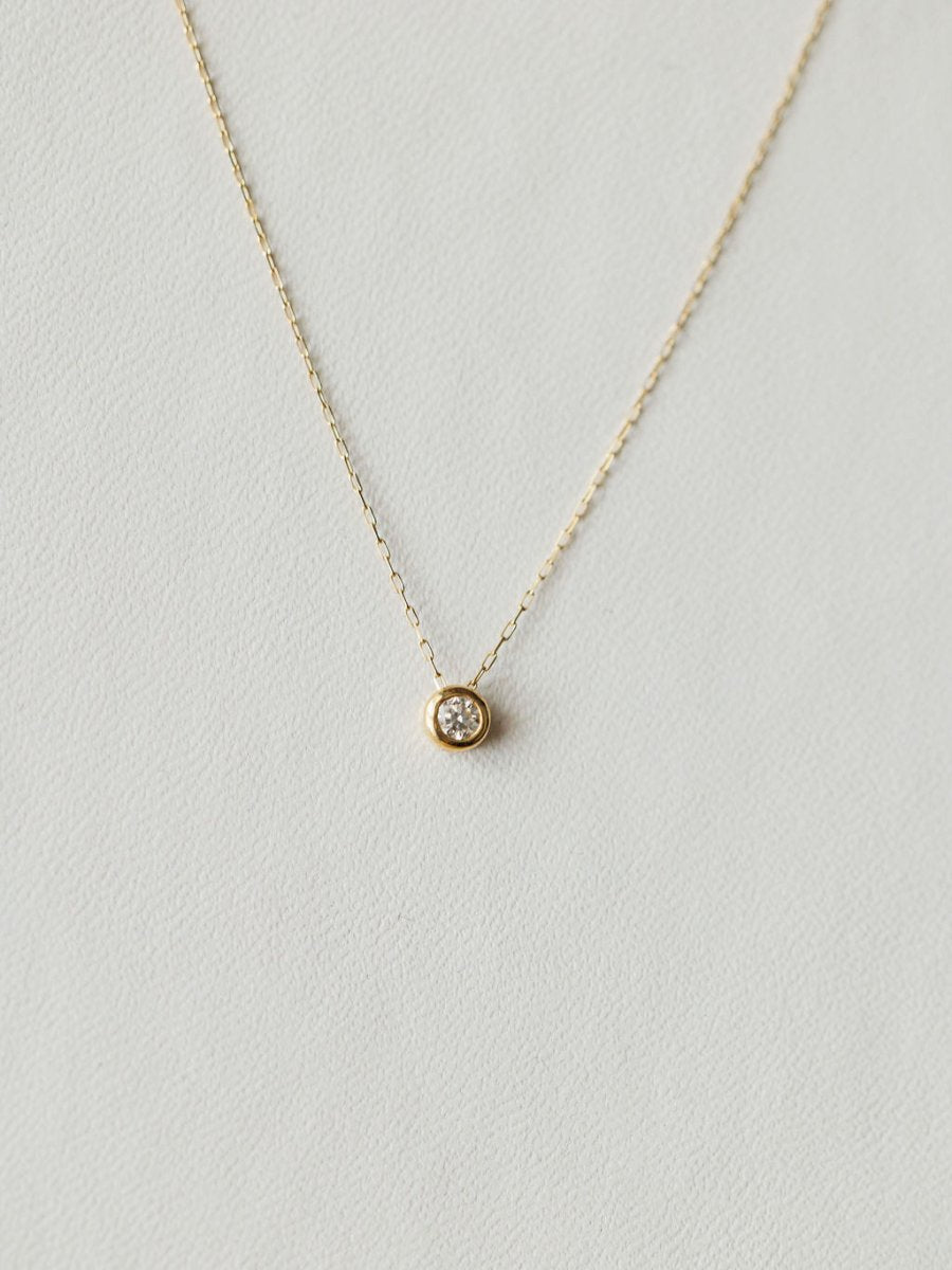 The Petite Diamond Necklace {Gold} by Savannah Sevens western life{&}style features a small round bezel-set diamond on an 18K yellow gold chain, shown against a light neutral background.