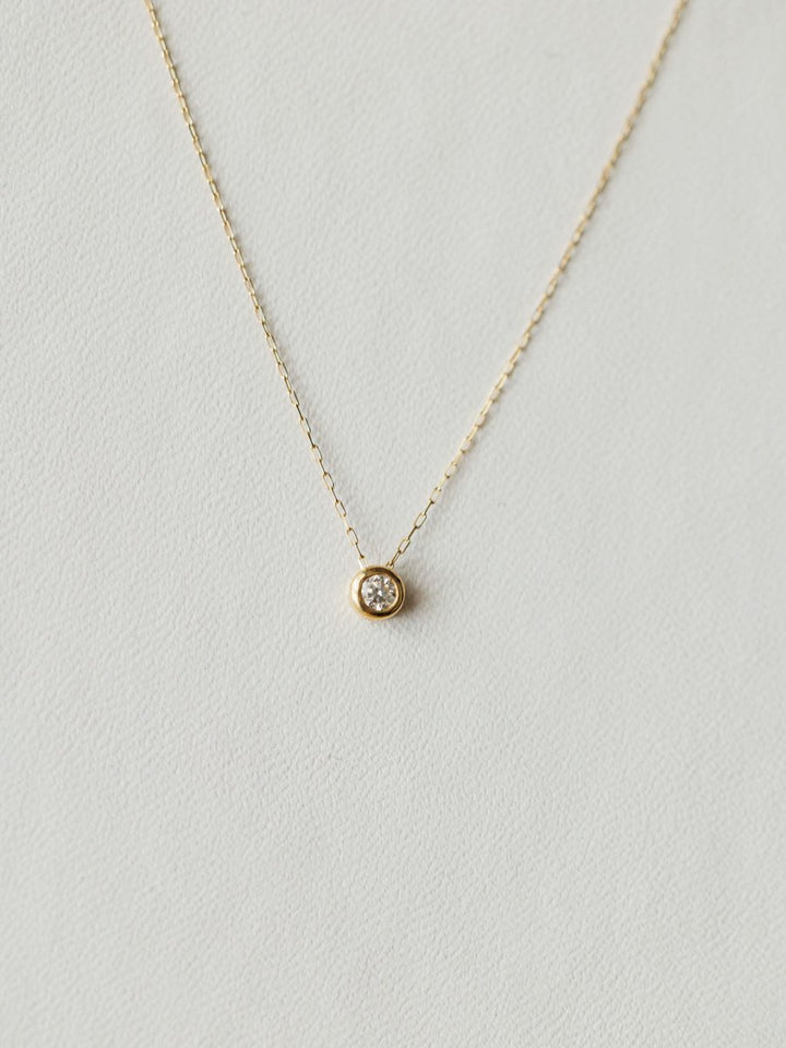 The Petite Diamond Necklace {Gold} by Savannah Sevens western life{&}style features a small round bezel-set diamond on an 18K yellow gold chain, shown against a light neutral background.