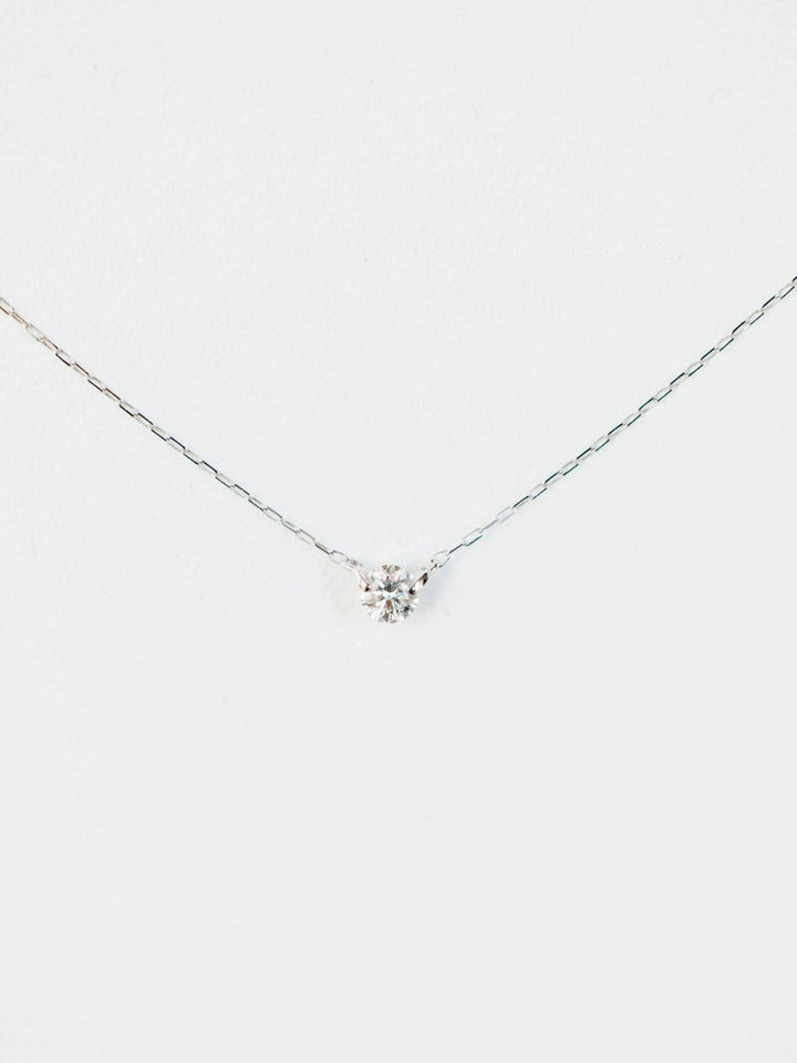 The Petite Diamond Necklace {White Gold} by Savannah Sevens western life{&}style features a delicate 18K white gold chain with a small natural round diamond pendant, displayed against a plain white background.