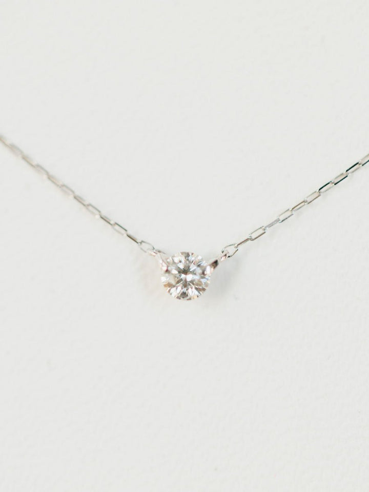 The Savannah Sevens western life{&}style Petite Diamond Necklace {White Gold} features a natural round solitaire diamond pendant set in 18K white gold, elegantly displayed against a white background.