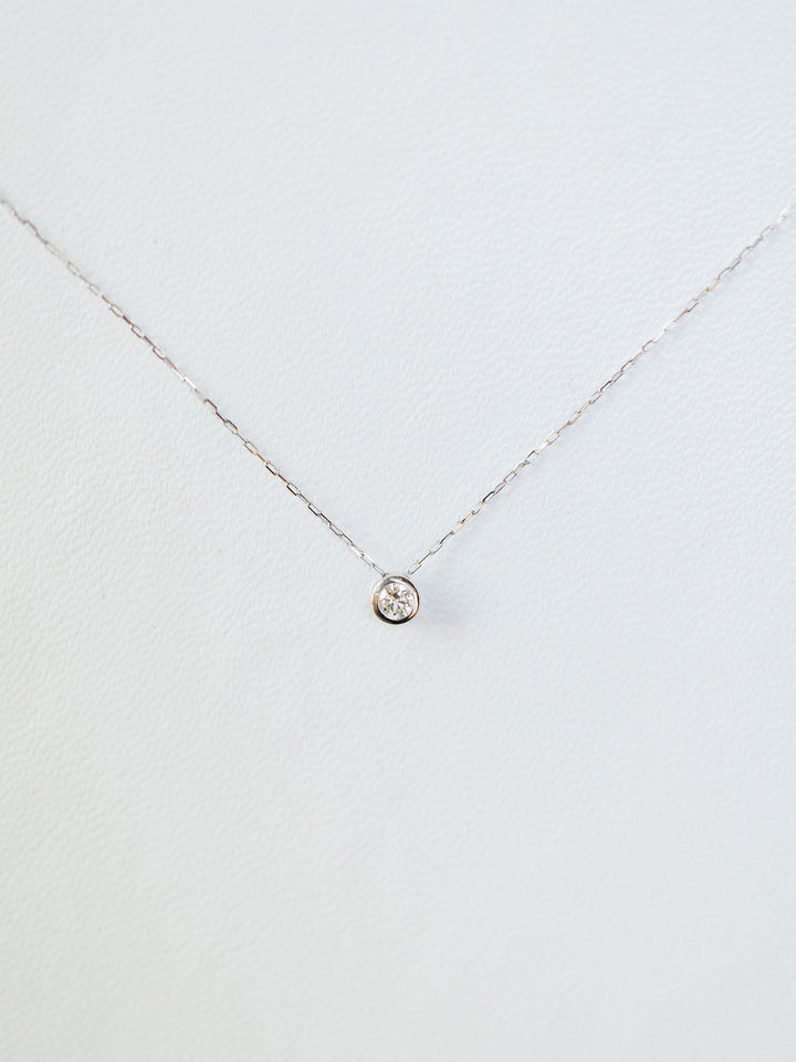 The Petite Diamond Necklace {White Gold} by Savannah Sevens western life{&}style features a natural round diamond solitaire in a simple bezel, crafted in 18K white gold and shown on a plain white background.