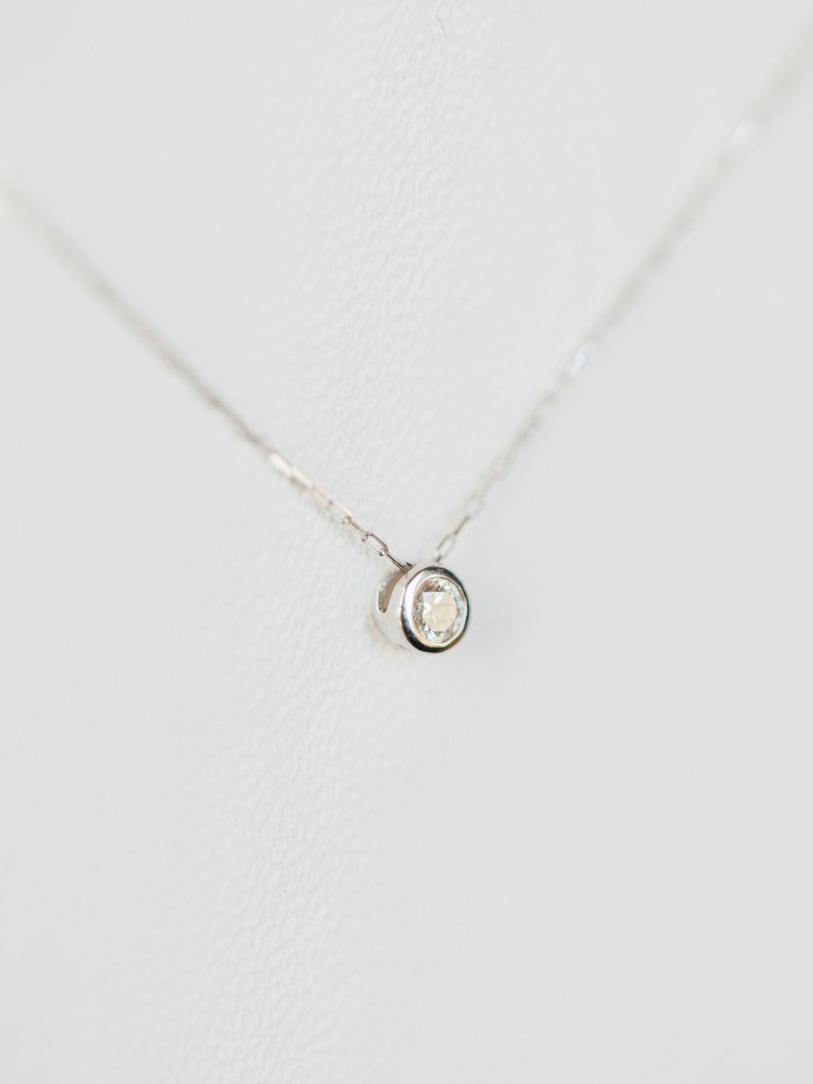 The Petite Diamond Necklace {White Gold} by Savannah Sevens western life{&}style features a small natural round diamond solitaire pendant in 18K white gold, displayed on a white background.