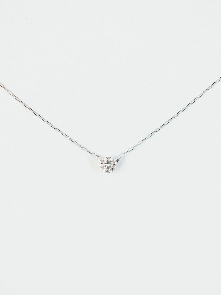 The Petite Diamond Necklace {White Gold} by Savannah Sevens western life{&}style features a delicate 18K white gold chain with a small natural round diamond pendant, displayed against a plain white background.