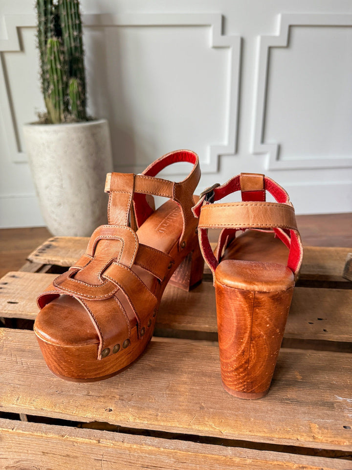 The Peyette by Savannah Sevens western life{&}style: tan leather strappy platform sandals with wooden heels, displayed on a pallet against a white textured wall and potted cactus. Made by BedStu. 