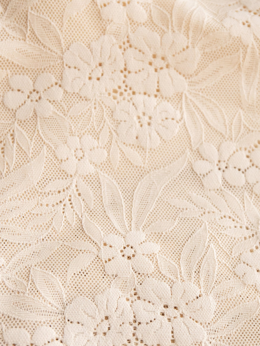 Close-up of the Pomona Bralette by Savannah Sevens western life{&}style, featuring cream-colored lace with an intricate floral and leaf pattern—delicate small flowers and leaves woven into a fine mesh, perfect with its adjustable straps.