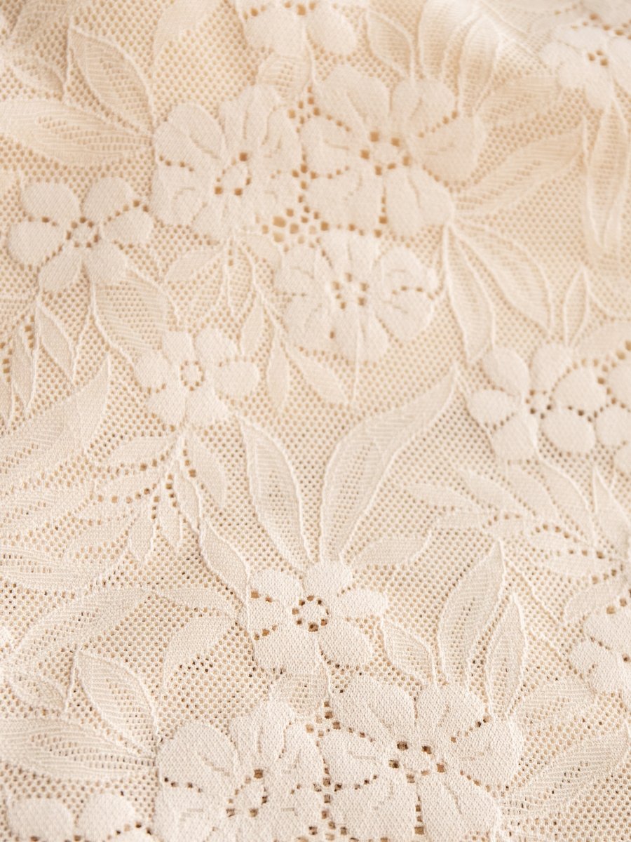 Close-up of the Pomona Bralette by Savannah Sevens western life{&}style, featuring cream-colored lace with an intricate floral and leaf pattern—delicate small flowers and leaves woven into a fine mesh, perfect with its adjustable straps.
