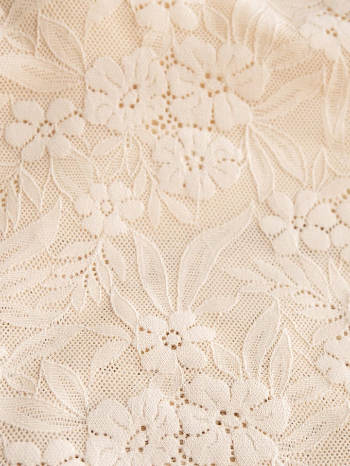 Close-up of the Pomona Bralette by Savannah Sevens western life{&}style, featuring cream-colored lace with an intricate floral and leaf pattern—delicate small flowers and leaves woven into a fine mesh, perfect with its adjustable straps.