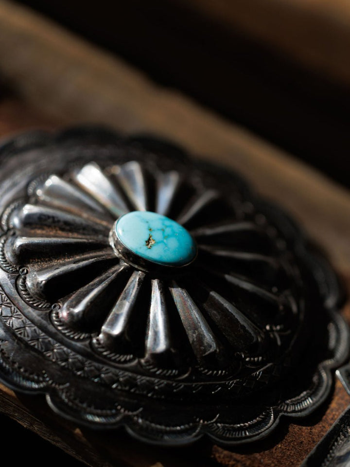 A close-up of the Portales Belt by Savannah Sevens western life{&}style, showcasing a vintage sterling silver concho with scalloped edges, detailed engravings, and a central round turquoise stone—ideal for a #8 Turquoise concho belt.