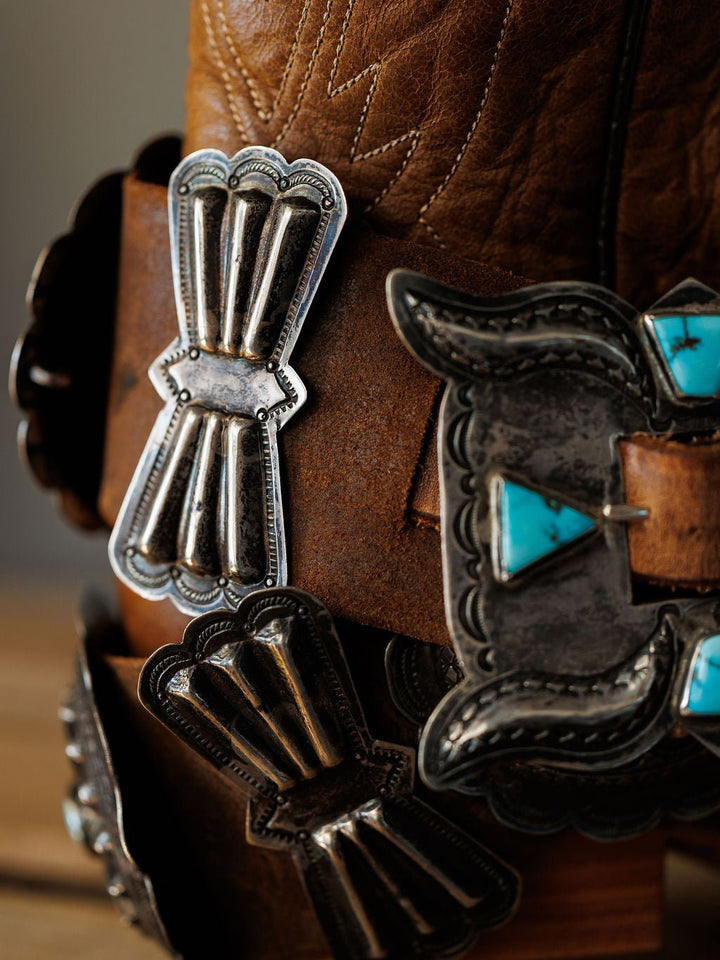 Close-up of Portales Belt by Savannah Sevens western life{&}style, a brown leather cowboy boot accessory adorned with vintage sterling silver and #8 Turquoise concho belt, featuring intricate engraved patterns.
