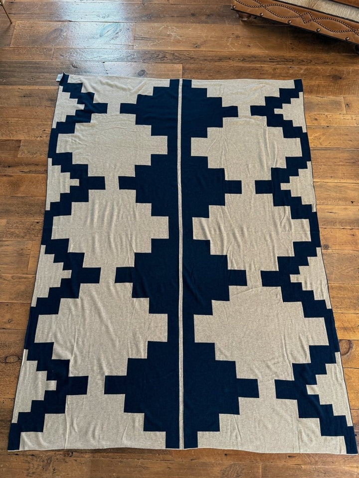 The Presidio Throw Blanket {Midnight Navy} by Savannah Sevens western life{&}style features a reversible geometric zigzag pattern in black and beige, creating a symmetrical, stylish look when laid flat on any floor.