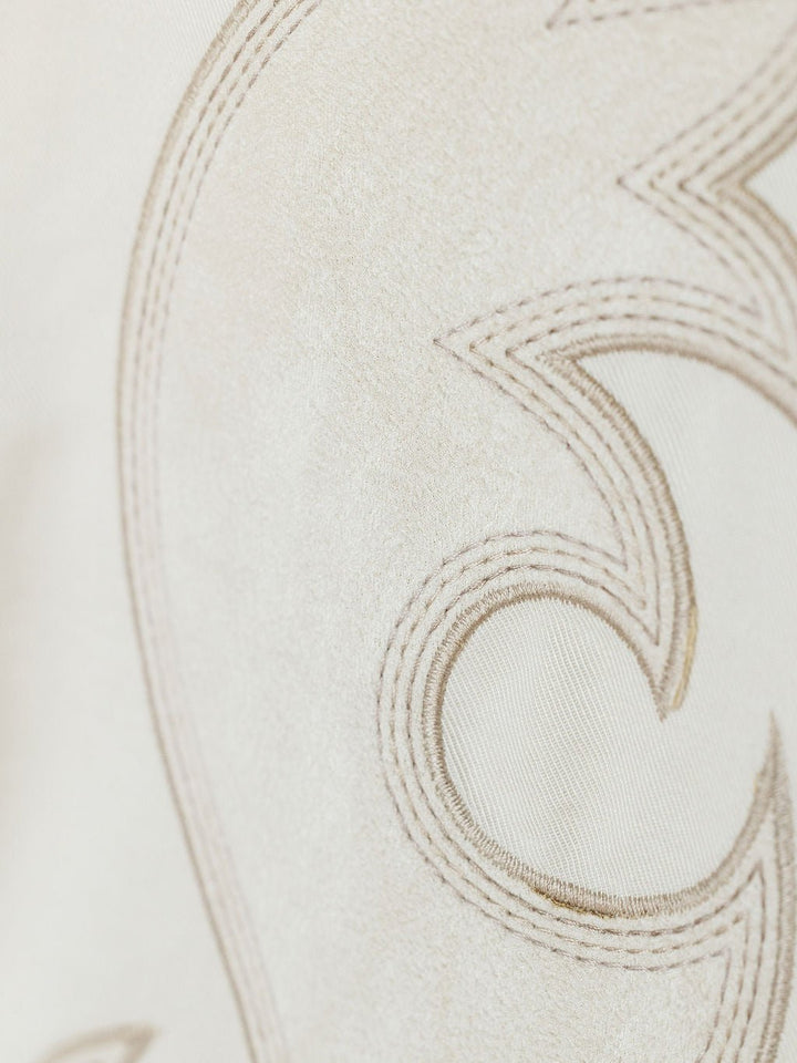 Close-up of cream faux suede from the Savannah Sevens western life{&}style Questa Boot Stitch Jacket, showing embroidered light brown abstract curves and points, with detailed fabric and stitching visible.
