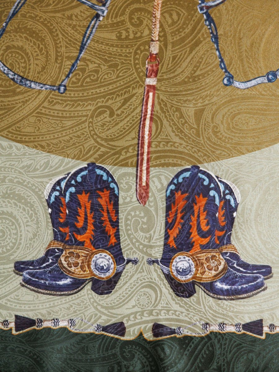 Illustration of decorated cowboy boots with spurs and an ornate belt above, set on a green and brown paisley backdrop, inspired by the luxury Ranch Gear Wild Rag from Savannah Sevens western life{&}style.