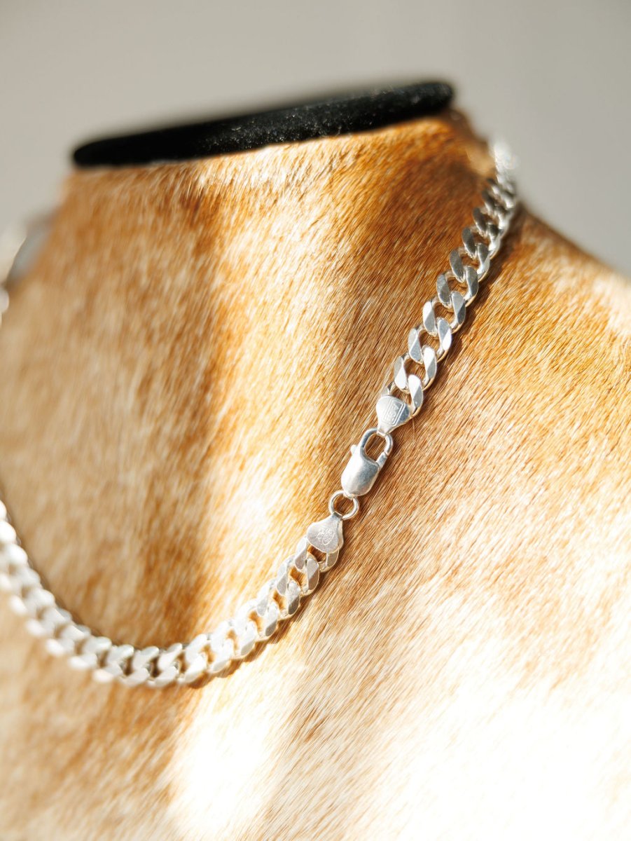 A close-up of the Ranchero Necklace by Savannah Sevens western life{&}style, featuring a sterling silver snaffle bit on a 925 Italy curb link chain, displayed on a tan, fur-covered bust in bright natural light.