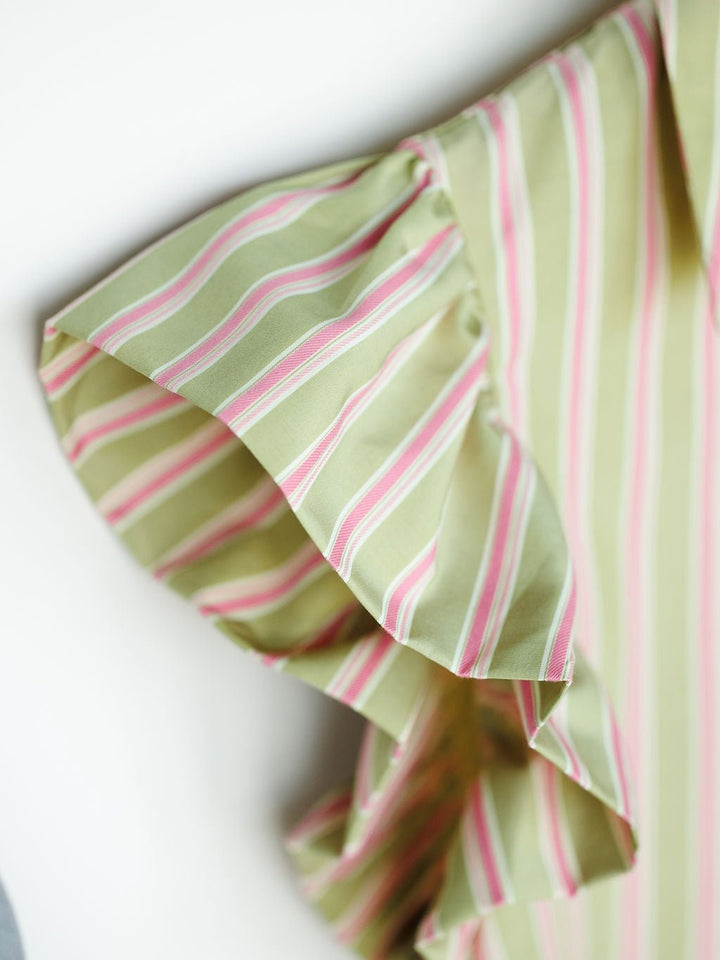 Close-up of the ruffled short sleeve on The Rayas sage pink blouse by Savannah Sevens western life{&}style, featuring white and pink vertical stripes. Soft fabric and flutter sleeve add a stylish, decorative touch.