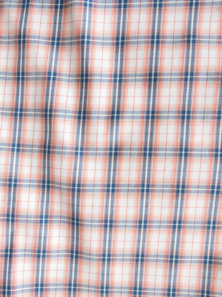 White fabric with a plaid pattern featuring thin orange and blue lines intersecting to form squares, and a subtly textured surface from slight wrinkling—perfect for the Raymore Ariat Men's Plaid Button Up by Savannah Sevens western life{&}style.