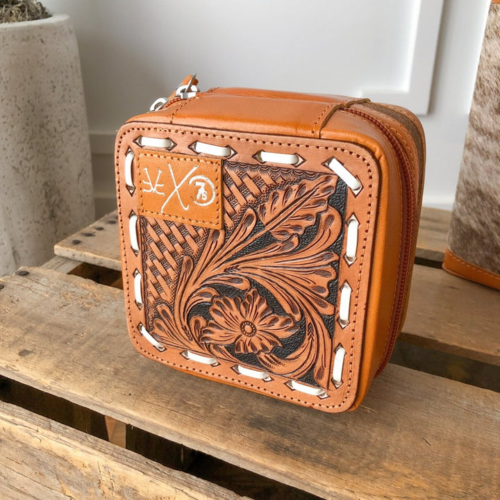 The Rialto Tooled Leather Mini Travel Jewelry Case by Savannah Sevens western life{&}style features intricate floral and basketweave designs, white stitching, and a subtle embossed logo—a stylish cowhide pouch for your essentials.