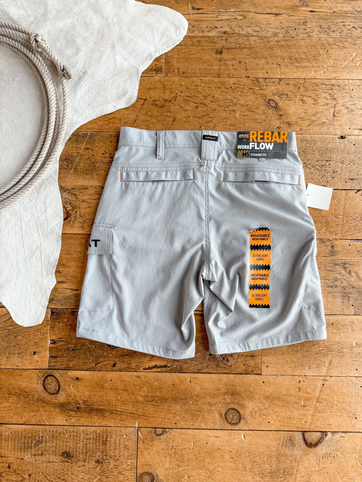 Rockville Ariat Men's M5 Shorts by Savannah Sevens western life{&}style are laid flat on a wooden floor. These men’s work shorts feature back pockets and durable Durastretch fabric. A white rug with rope detail is nearby. Tags are attached.