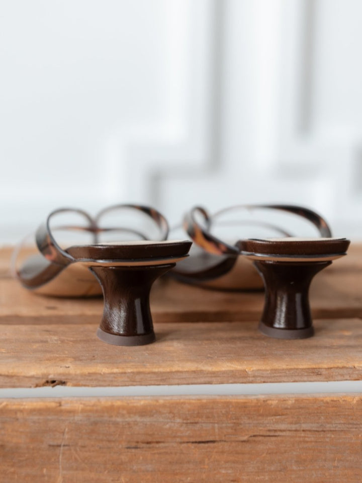 A close-up of The Roslyn multi-strap heeled sandals by Savannah Sevens western life{&}style, featuring a square toe and unique low heels, displayed on a wooden surface and shown from the back.