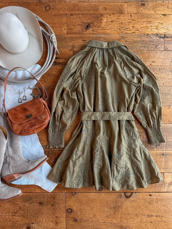 Flat lay of a western look on wood: Savannah Sevens western life{&}style Roswell Olive Eyelet Long Sleeve Dress, taupe cowboy boots, tan suede handbag, silver earrings, white cowboy hat, and a coiled rope.