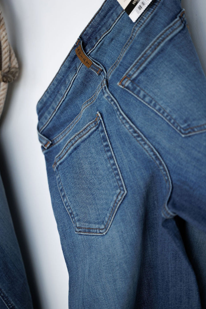 A close-up of The Sadie Perfect Rise Wide Leg Crop Jean by Savannah Sevens western life{&}style shows blue denim with a back pocket, waistband, part of the label, visible stitching, classic design, and medium light wash.