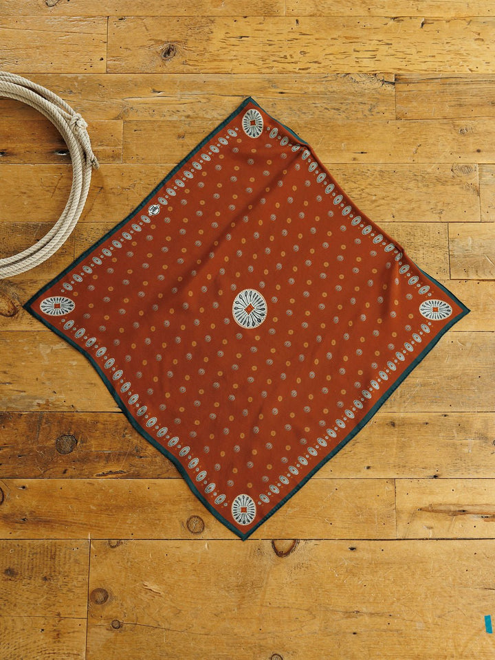 San Miguel Silk Scarf, a square rust orange neck scarf with a repeating cream dot pattern and a decorative floral border in a Southwest style.