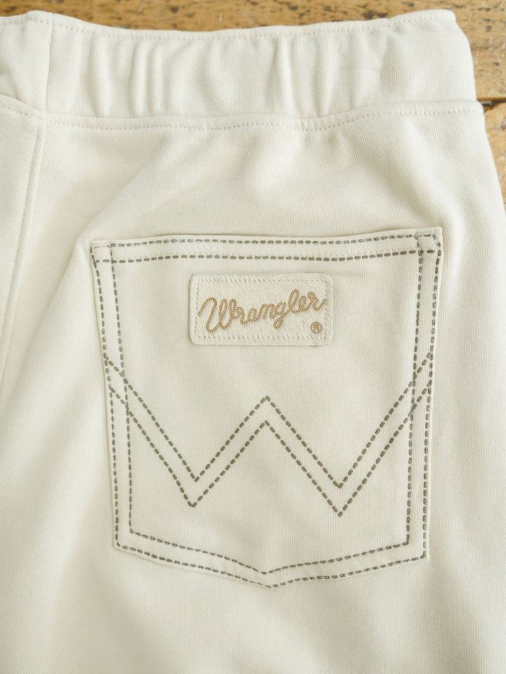 Close-up of a cream-colored pocket with brown stitching and a logo patch above a stitched W, from the Sanger Natural Boot Stitch Set by Savannah Sevens western life{&}style. This relaxed fit piece is crafted from denim or similar material.