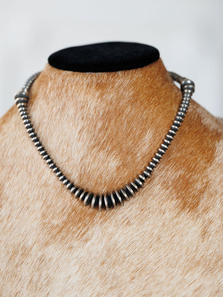 A Sarita Graduated Navajo Pearl Necklace featuring round, dark metallic beads on a display bust.