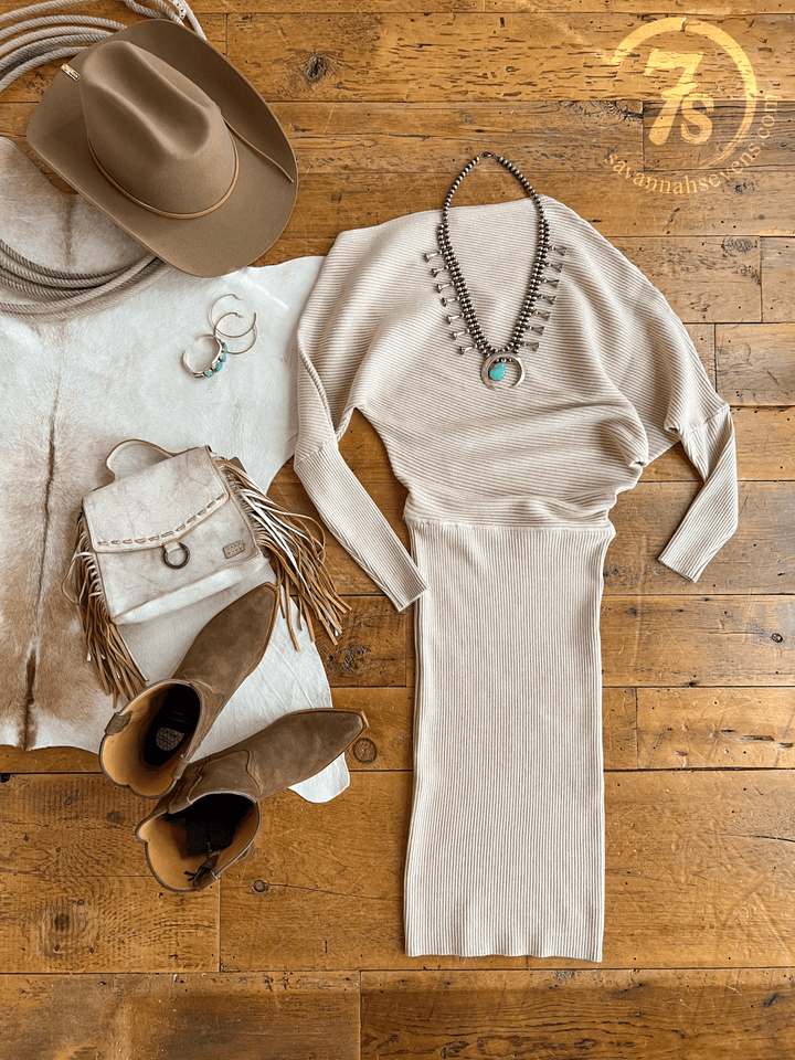 The Shawnee Hills Oatmeal Ribbed Long Sleeve Dress by Savannah Sevens western life{&}style is styled with brown suede boots, a fringed bag, turquoise jewelry, silver hoops, a tan cowboy hat, coiled rope, cowhide rug, and features the Savannah Sevens logo.